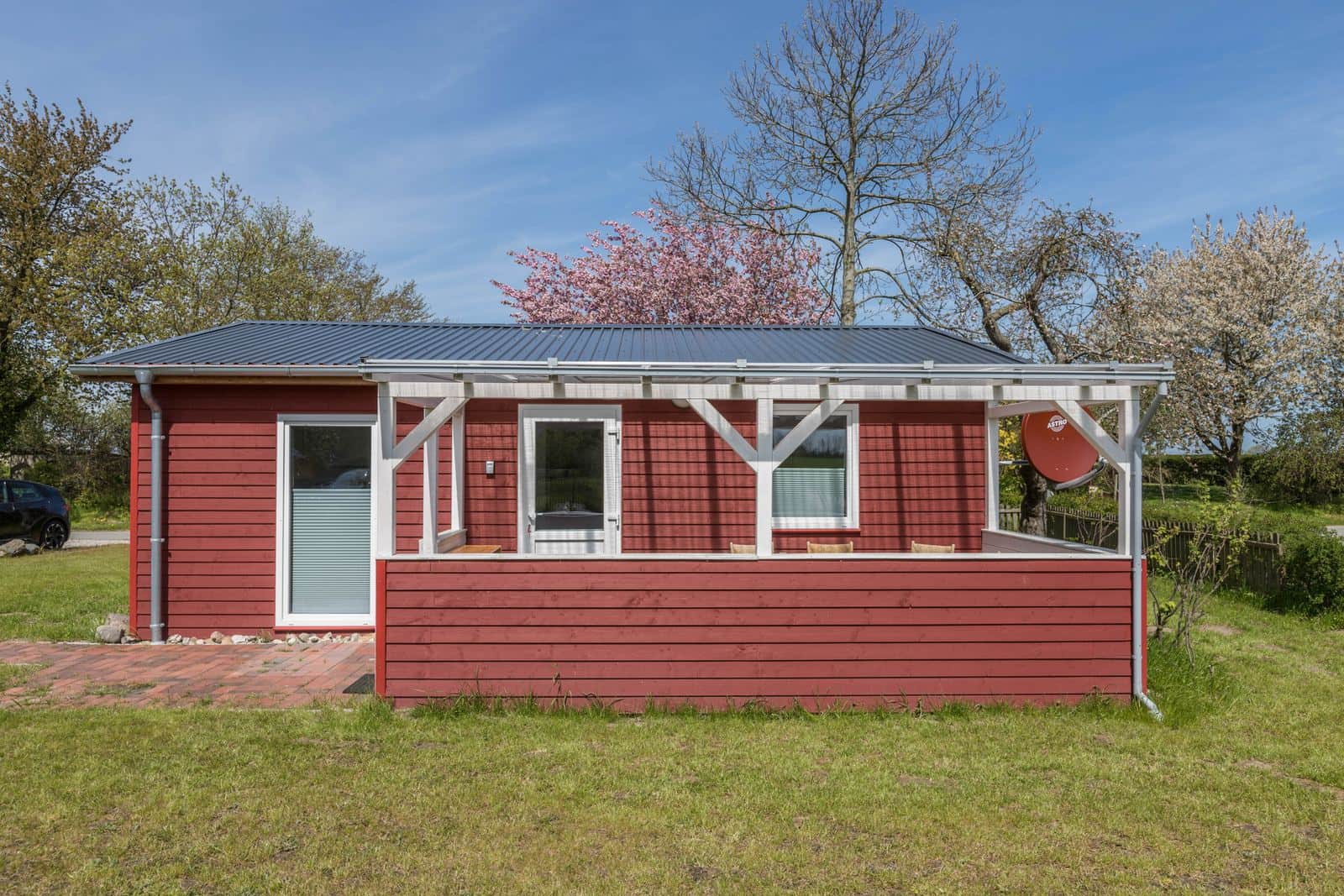 Holtdeel from the front: the covered veranda on white posts runs the whole length of the house, with a brick path and lawn in front.
