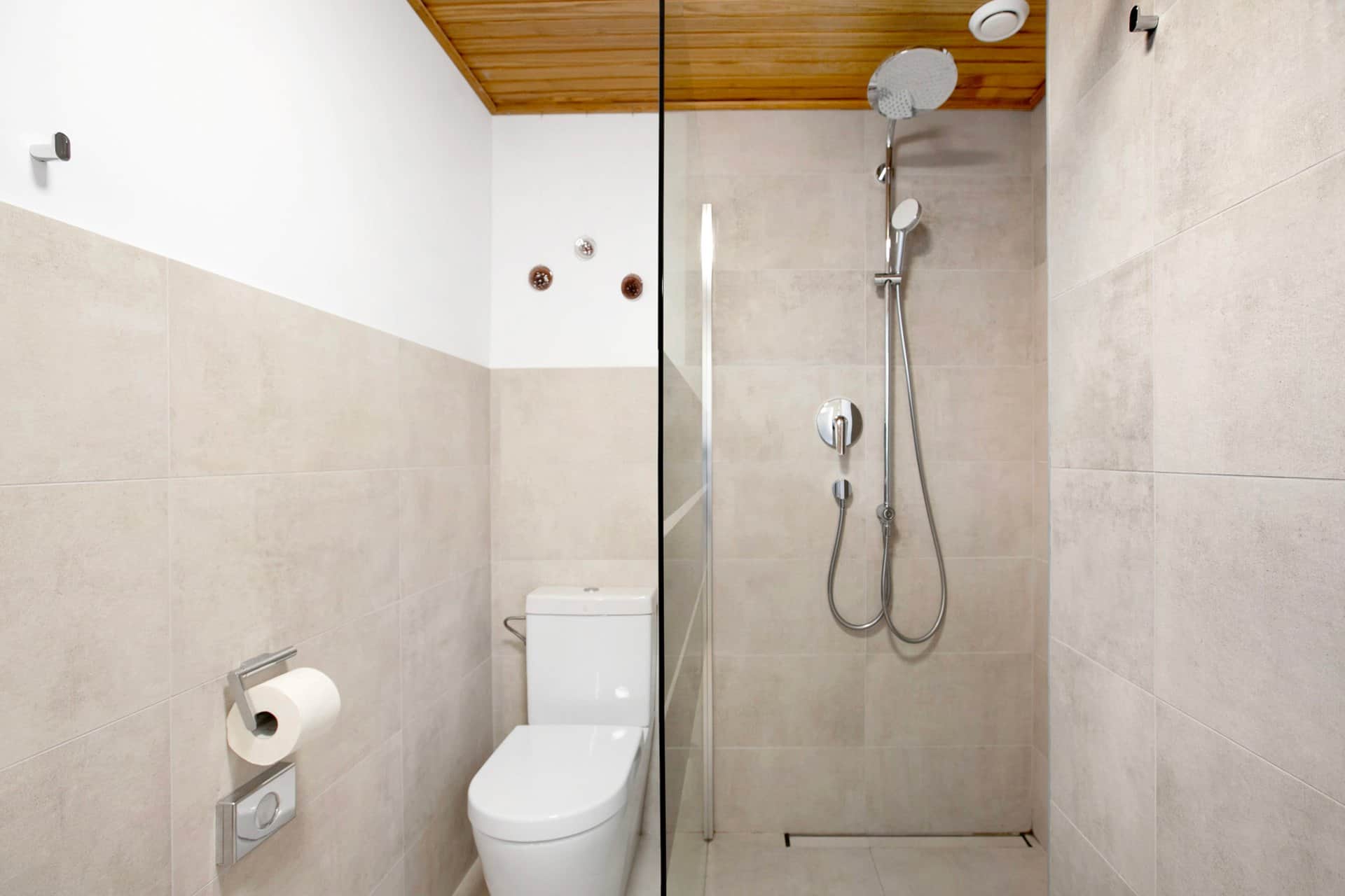 The shower in the second bathroom: a walk-in shower behind a glass panel with the WC to the left, surrounded by large grey tiles.